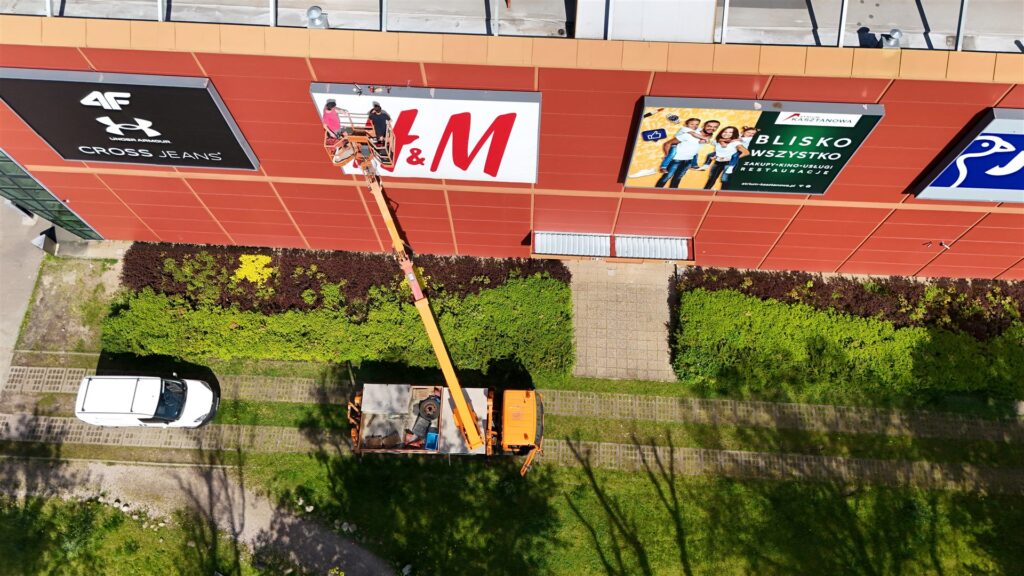 Montaż szyldu H&M na elewacji galerii handlowej - zdjęcie z drona Nova Electro